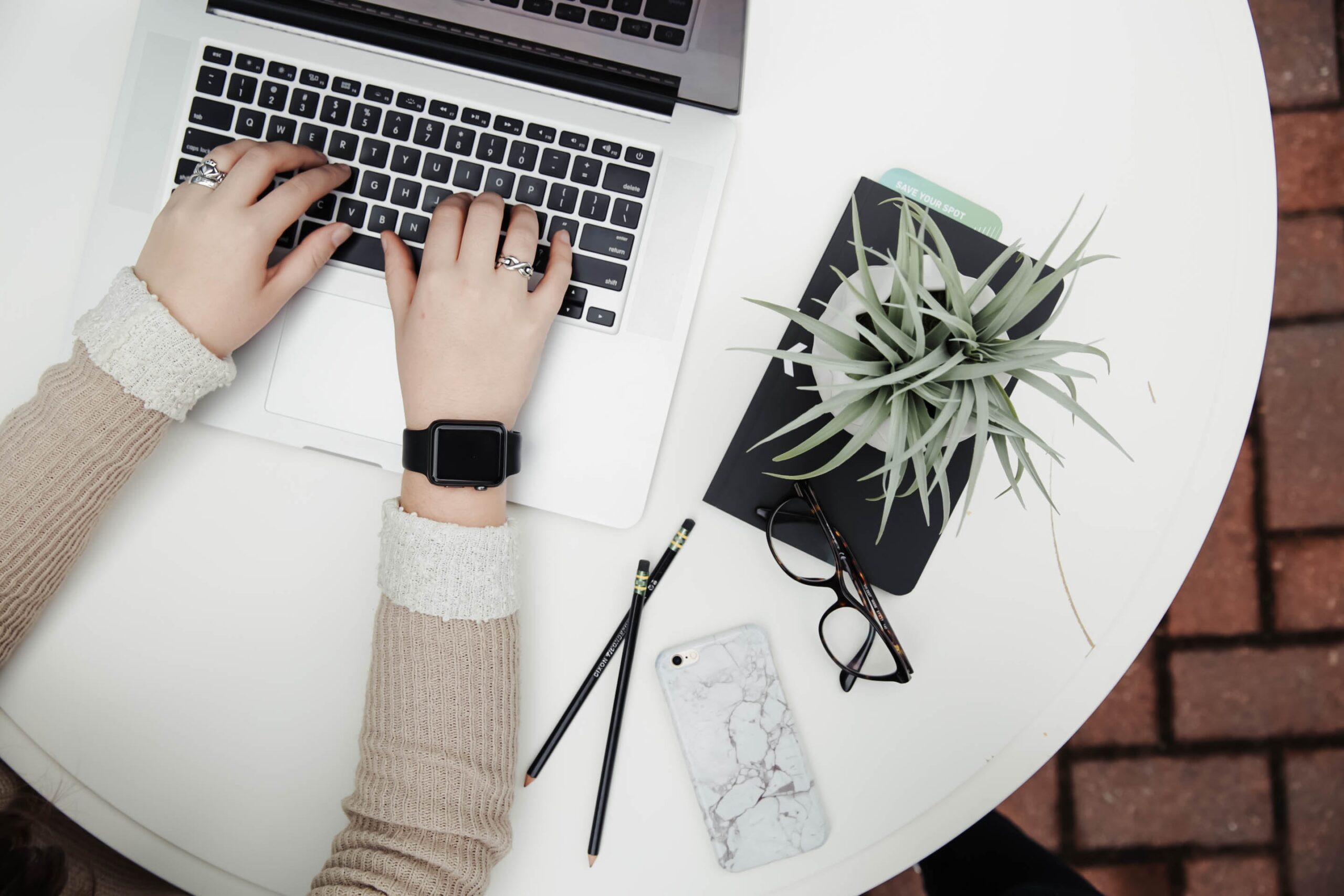 Image of a person on a laptop, next to some plants on a table.